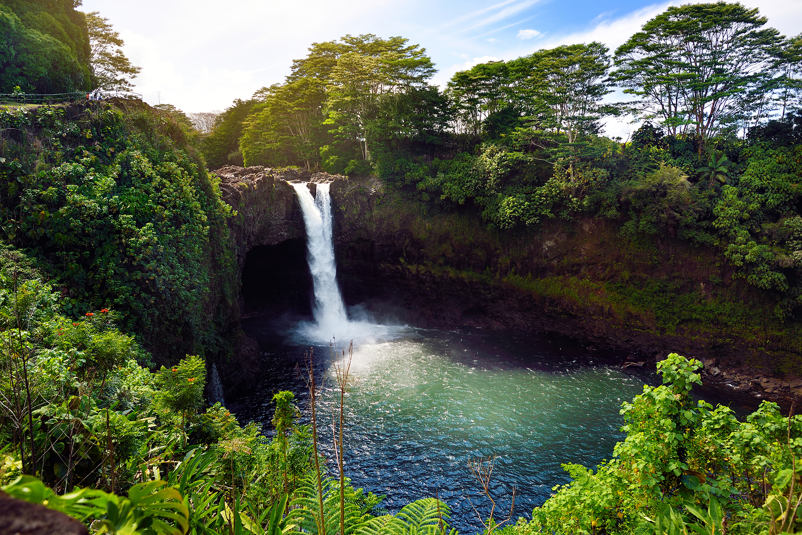 Majesitc Rainbow Falls waterfall in Hilo Wailuku River State Park Hawaii. The falls flows over a natural lava cave the mythological home to Hina an ancient Hawaiian goddess.