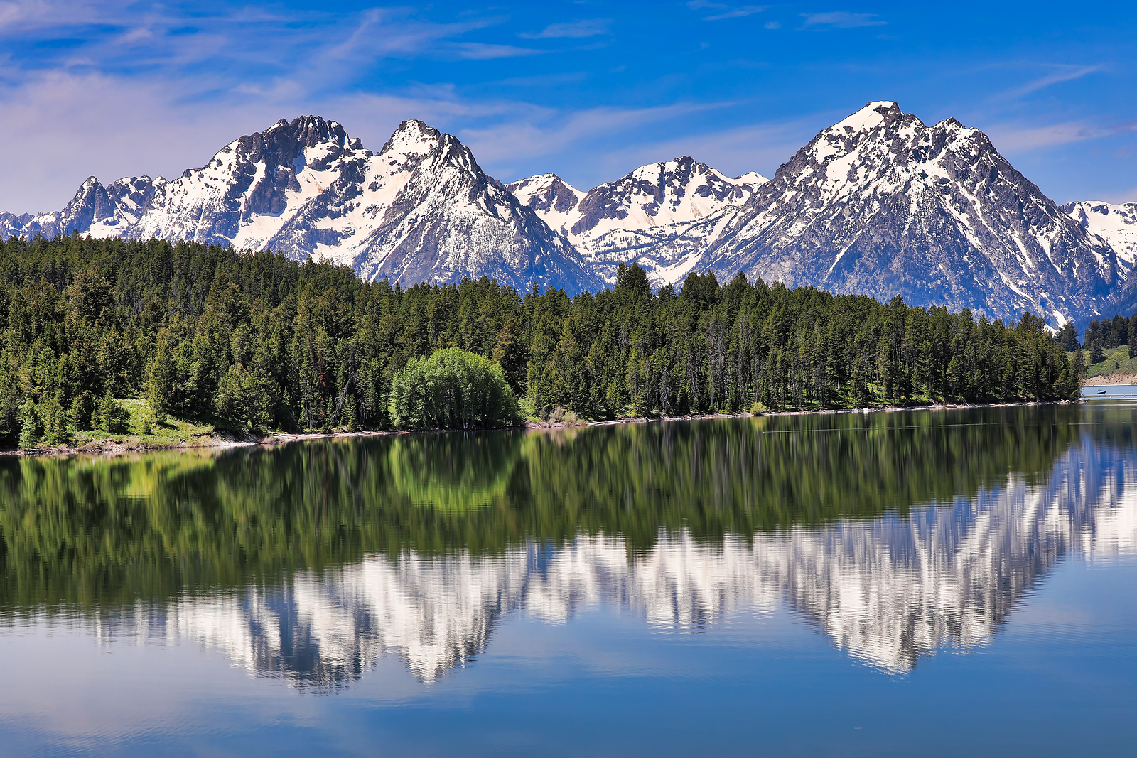 The Grand Tetons in Wyoming are reflected in the still waters of Jackson Lake.  This is a popular vacation destination in the Yellowstone and Jackson Hole areas.